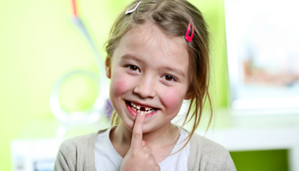 Girl smiling and pointing at the gap in her teeth