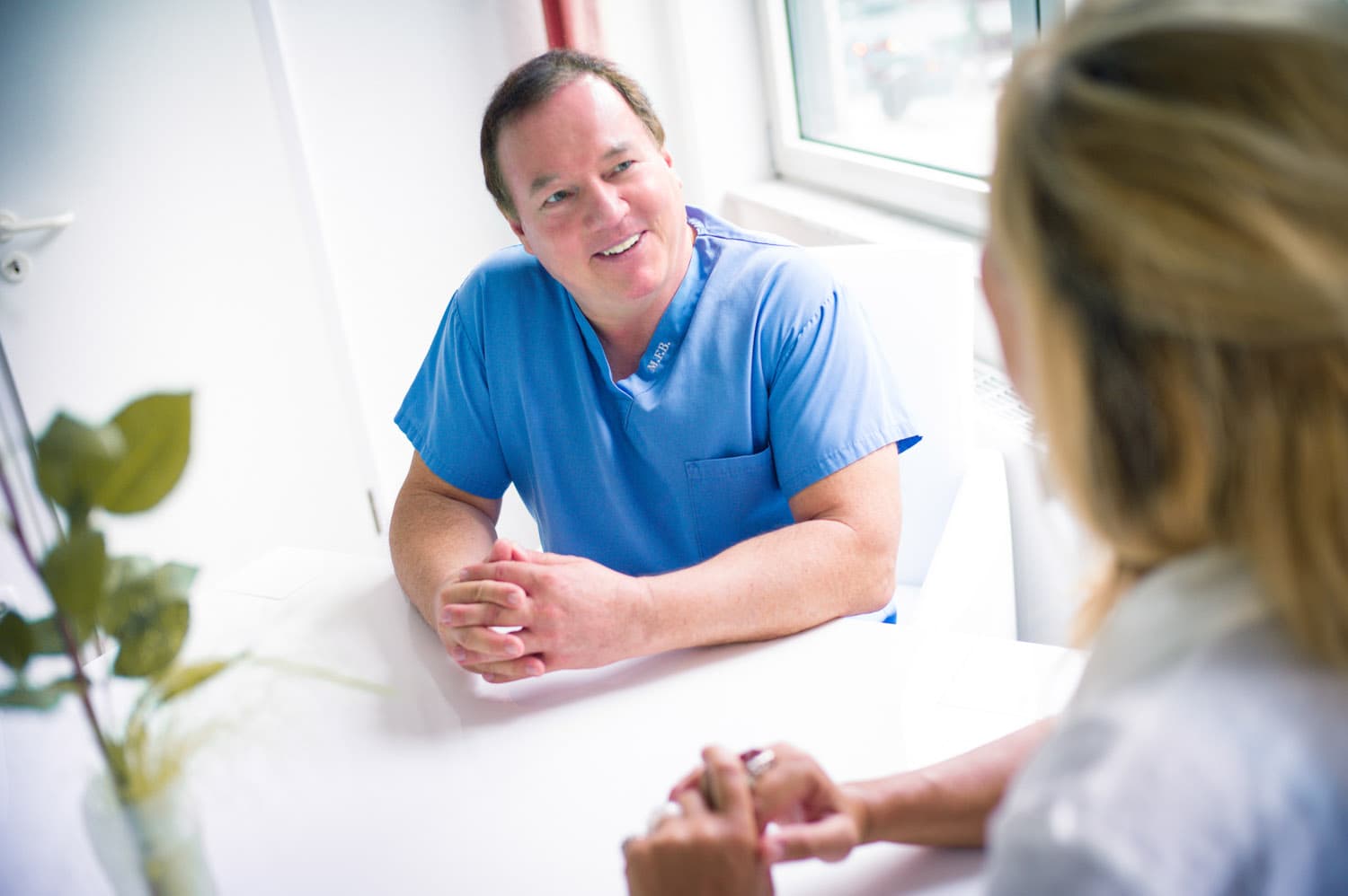 Professor Bender im Gespräch mit einer Patientin am Schreibtisch